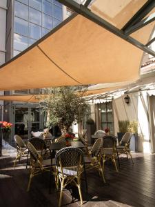 a patio with tables and chairs and a large umbrella at Hôtel Alexandra in Lyon