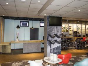 a lobby with a bar with a tv on a wall at ibis Egletons in Égletons