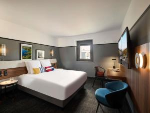a hotel room with a bed and a blue chair at Mercure Caen Centre Port De Plaisance in Caen +94 photos