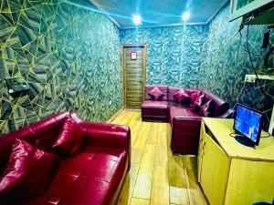 a living room with red leather couches and a laptop at Hotel Diamond View in Greater Noida