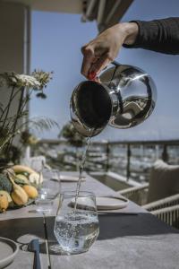 a person pouring water into a wine glass at Akari - Luxury Apartment in Preveza