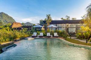 a swimming pool with chairs and a building at Anandinii Resort Sidemen by AGATA in Sidemen