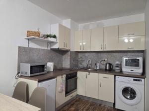 a kitchen with white cabinets and a washer and dryer at Azaria in Hisarya +10 photos