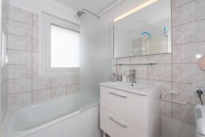 a white bathroom with a sink and a tub at La Proue , duplex face mer in Arzon