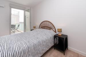 a bedroom with a bed and a table with a lamp at La belle étoile - 4 pers - balcon in Vannes