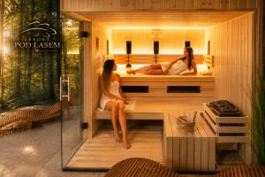 two women sitting in a sauna in a hotel room at Resort Pod Lasem in Kolonowskie