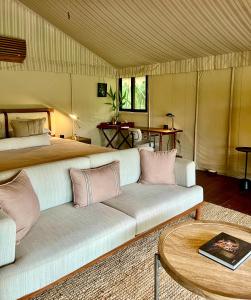 a bedroom with a bed and a couch and a table at Bagh Villas I Kanha in Kānha