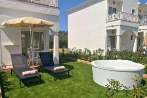 a garden with a tub and two chairs and an umbrella at Garden Saladina - Adults Only in Playa de Muro
