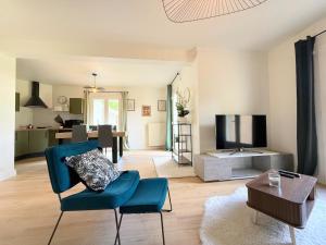 a living room with a blue chair and a tv at Le Cocon de Vabre, maison calme in Onet le Château