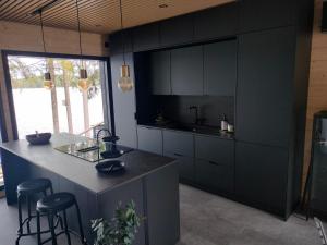 a kitchen with black cabinets and a counter with stools at Villa Vaalanto in Pomarkku