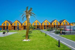 a palm tree in front of a row of houses at Comfortable holiday home, pool, sauna, jacuzzi in Kopań
