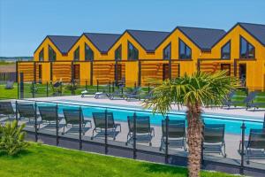 a pool with chairs and a palm tree in front of a building at Comfortable holiday home, pool, sauna, jacuzzi in Kopań