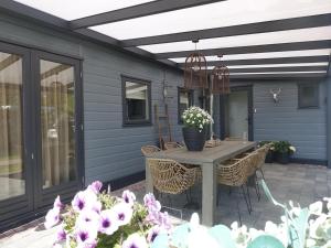 a patio with a table with chairs and flowers at Vechtdal Chalet de Wilg in Rheezerveen