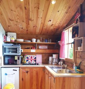 a kitchen with wooden cabinets and a sink and a microwave at Le Chalet du Clos Giot in Saint-Vaast-la-Hougue