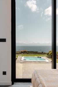 a bedroom with a view of a swimming pool and the ocean at Casa Al Mare in Canto da Areia