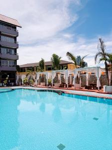 a large swimming pool with a hotel in the background at The Holiday Resort Pattaya in Pattaya