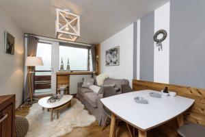 a living room with a couch and a table at Les Lauzes - Freeloc Immobilier in Les Menuires