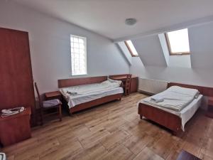a room with two beds and a chair and windows at Hostel RAV in Tomaszów Mazowiecki