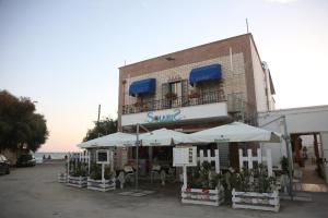 a building with tables and umbrellas in front of it at Pensione Solaris in Torre Lapillo