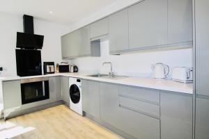a white kitchen with a sink and a dishwasher at Penthouse new 2 bed 2 apartment in Basingstoke +14 photos