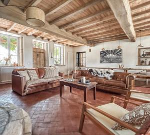 a living room with leather couches and a table at La Ferme du Domaine de Bassol – Piscine & Billard in Mézériat