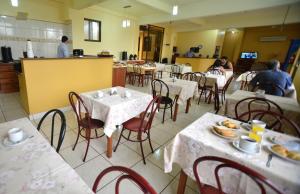 a restaurant with tables and chairs with people sitting at them at Hotel Lilian in Puerto Iguazú