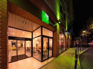 a store front with a green sign on the side of a building at ibis Styles Perpignan Centre Gare in Perpignan
