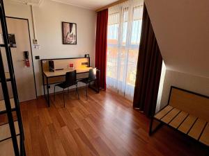 a room with a desk and a table and a window at ibis Hotel Nürnberg Altstadt in Nuremberg