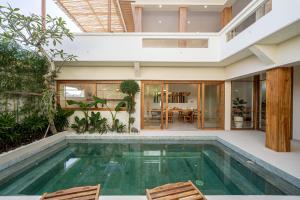 an indoor pool with two chairs and a house at Villa Ume Seseh in Munggu