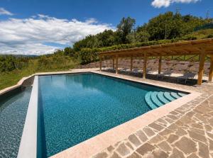 a swimming pool with a pergola and blue water at Tenuta di Valmarino - Adults only in Corciano
