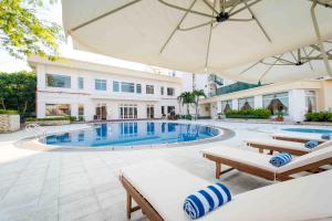 a swimming pool with two chairs and an umbrella at Palace Hotel Vung Tau in Vung Tau