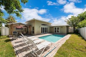 a house with a swimming pool and lounge chairs at Home with pool by Dream Vacation in Fort Lauderdale