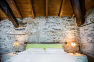 a bedroom with a bed in a stone wall at Borgo Molina in Faggeto Lario 