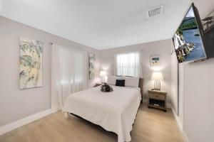 a white bedroom with a white bed and a tv at Beach Apart by Dream Vacation unit 1 in West Palm Beach +20 photos
