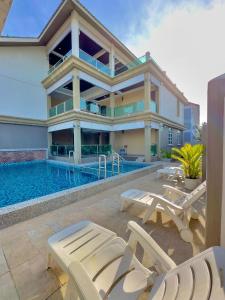 a house with a swimming pool and some chairs at Grand Village Inn in Pantai Cenang