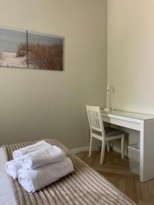 a bedroom with a desk and a bed with towels at Hotel Miramar in Sopot