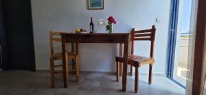 a table and two chairs with a bottle of wine and flowers on it at Marika Apartments in Mastihari
