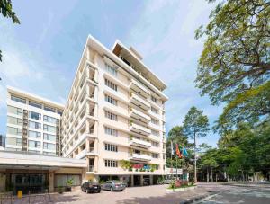 a large white building with cars parked in front of it at Rex Hotel Vung Tau in Vung Tau