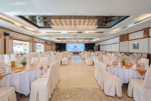 a banquet hall with white tables and chairs and a screen at Rex Hotel Vung Tau in Vung Tau +59 photos