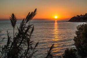 a sunset over the ocean with the sun setting at Paris-Irini Studios And Apartments in Plomarion