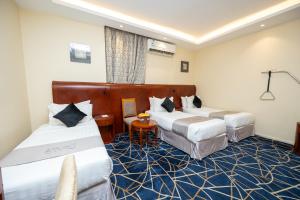 a hotel room with two beds and a table at Al Manara Ewaa Hotel in Mecca +44 photos