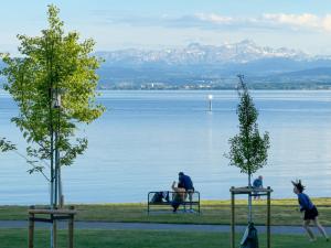 a group of people sitting on a bench by the water at Bodenseehäusle in Immenstaad am Bodensee