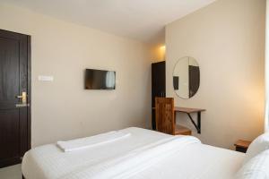 a bedroom with a white bed and a mirror at Hotel Vista by Booksy One Kollam Near Kollam Bypass in Kollam
