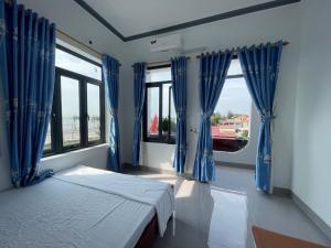 a bedroom with blue curtains and a bed and windows at Khách Sạn Long Dung in Nam Khê