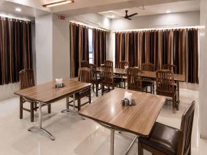 a dining room with wooden tables and chairs at Hotel Apollo Sp Ring Road Odhav Ahemdabad in Ahmedabad