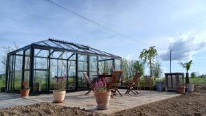 a glass greenhouse with chairs and plants on a patio at Gîte du Coupiat in Walcourt