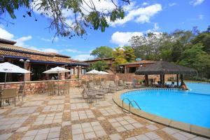 a pool with chairs and umbrellas next to a building at Portal Lençóis in Lençóis
