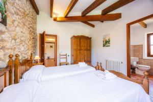 a bedroom with a large bed and a stone wall at Villa Cal Apostol in Pollença +26 photos