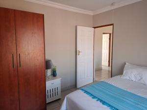 a bedroom with a bed and a wooden cabinet at CE Guesthouse in Vanderbijlpark