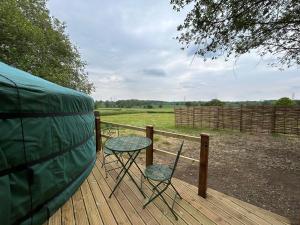 a table and two chairs on a deck with a tent at Jimmy's Yurt in Shenley +10 photos
